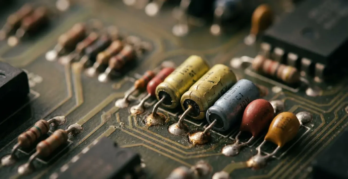 Extreme close-up of vintage synthesizer circuit board showing capacitor components and solder joints with visible aging