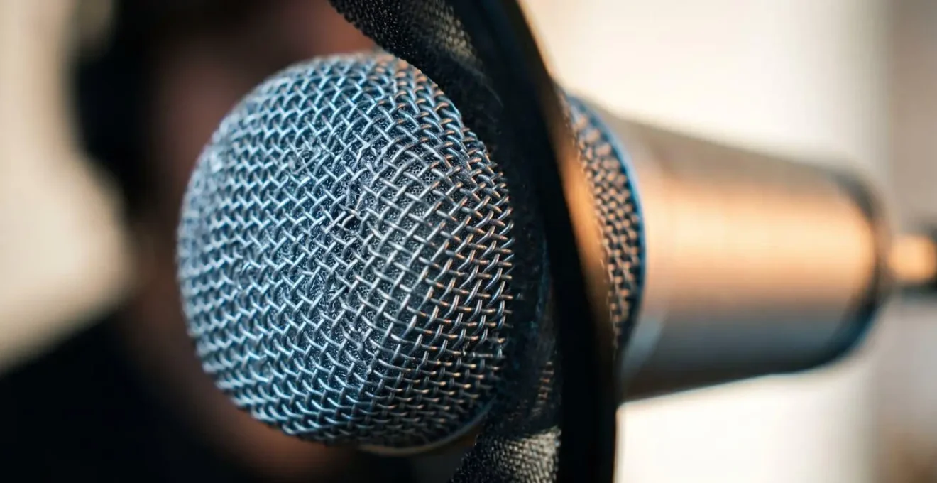 Close-up detail of professional condenser microphone with pop filter capturing intimate vocal recording setup