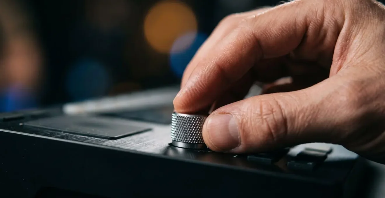 Close-up of musician's hand adjusting macro control knob on MIDI controller during live performance
