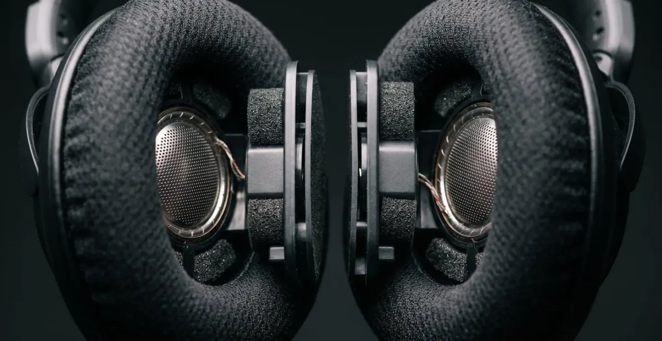 Macro close-up of over-ear stereo headphones showing dual driver architecture and acoustic isolation design