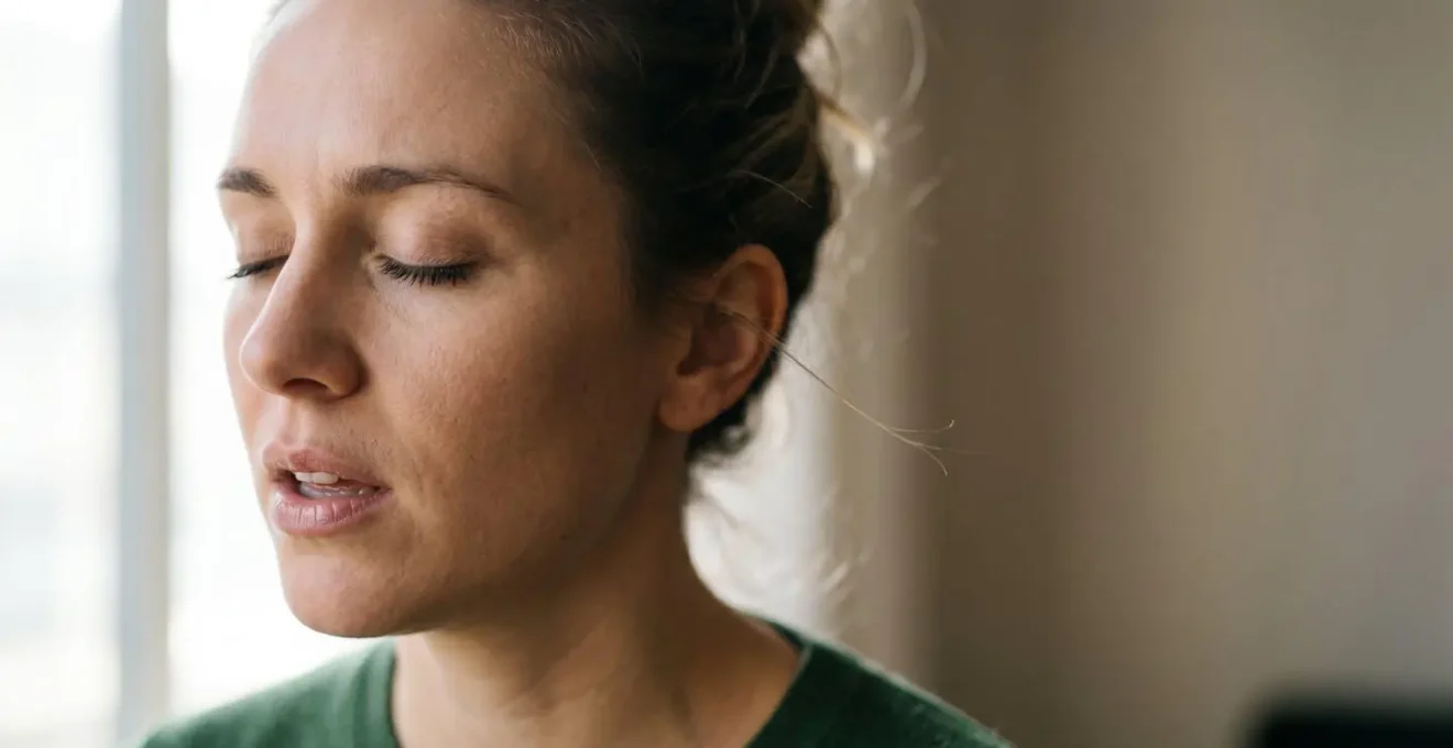 Human and emotional photograph of a meditation practitioner's face in profile with eyes closed during toning practice, capturing authentic emotion and inner focus